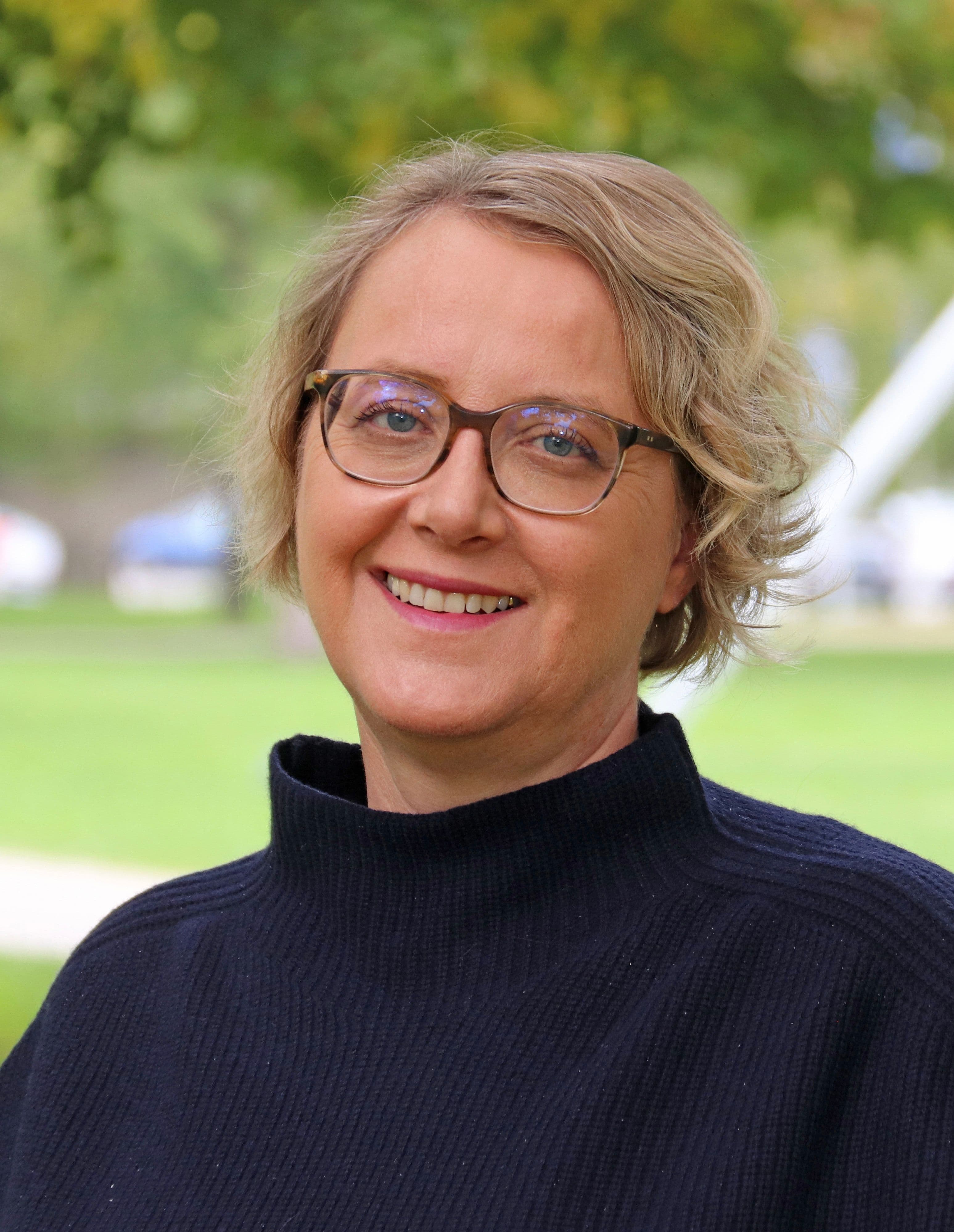 Vanessa Conze in schwarzem Pullover vor grüner Landschaft