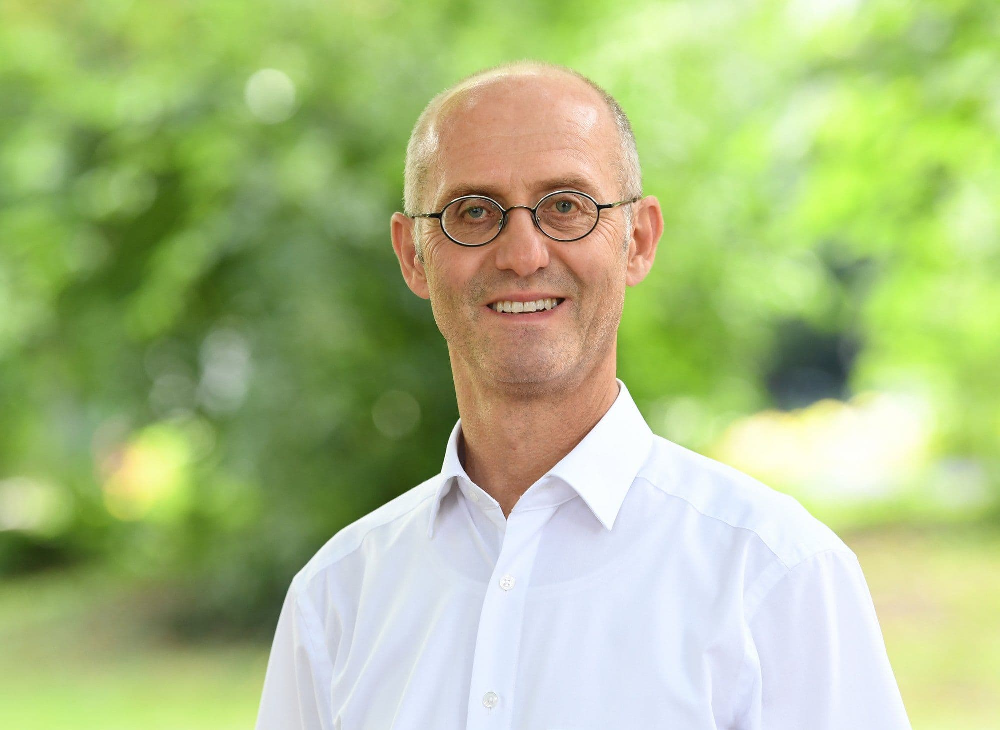 Dr. Ernst Wolfgang Becker vor einem grün bewaldeten Hintergrund